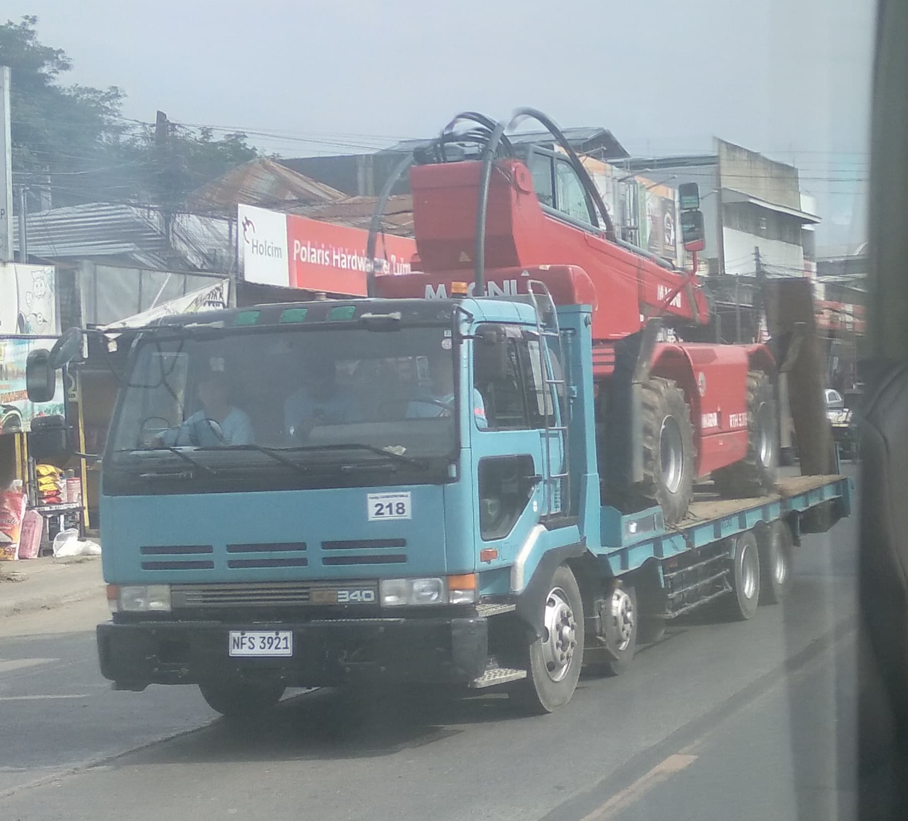 Nissan Diesel Big Thumb (First generation) CG340 8x4 self-loader/heavy equipment carrier truck carrying a MAGNI telehandler.
